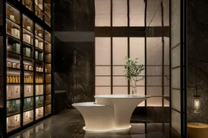 Elegant bathroom with a round table, double sinks, marble countertop, and a potted plant, surrounded by toiletries and personal care items