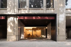 A modern lobby with a red awning, chairs, and a dining table, conveying a welcoming atmosphere
