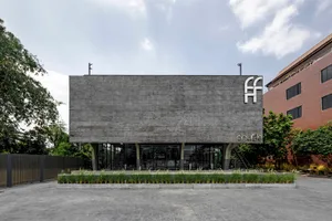 Modern building with a large gray concrete wall featuring windows with curtains, set against a bright daylight background