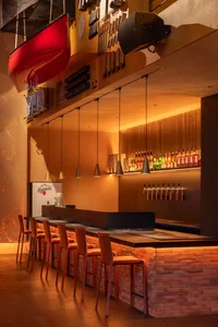 A warm and inviting bar area with a wooden counter, chairs, and bottles displayed behind the counter