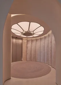 A warm hallway with pink and white walls, a wooden circular design element, and a doorway leading to another part of the building