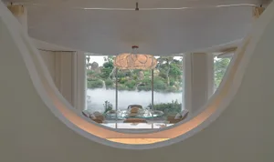 Bright and inviting living space with modern design, white walls, a glass dining table, and natural light from a large round window
