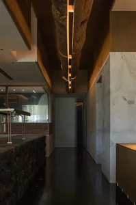 Modern kitchen with a stone finish, a dining table, chairs, and a refrigerator, set in a dimly lit space