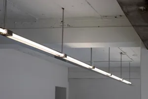 A bright and modern hallway with a long white corridor and lights hanging from the ceiling