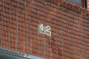 Exterior photo of a historic brick building with a red facade and a prominent number 12 on its side