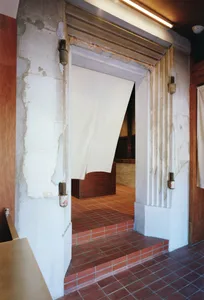 Warm and inviting interior space with red brick walls, white walls, and a hallway visible through an open door