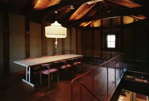 Warm and inviting open concept living area with a dining table, chairs, a couch, and wooden elements