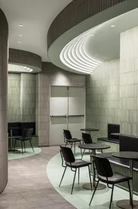 A restaurant interior with multiple tables and chairs, green tile walls, and a welcoming atmosphere