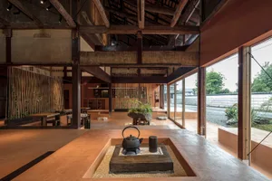 Cozy dining space with a wooden structure, stone fireplace, and potted plants, surrounded by chairs in a traditional Japanese-inspired setting