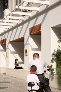 A daytime photo of a building with a wooden bench and natural light, featuring two people in the scene