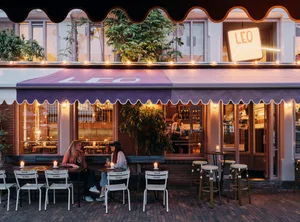 Outdoor dining area with tables and chairs under a large umbrella, featuring a relaxed and inviting atmosphere