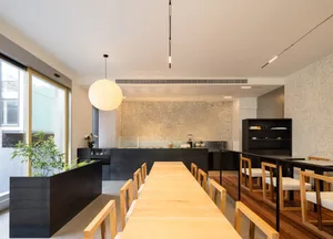 Warm and inviting open kitchen space with wooden floors, white walls, and a dining table, featuring appliances and potted plants