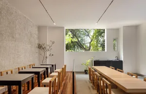 A restaurant dining area with multiple tables and chairs, potted plants, and a welcoming atmosphere
