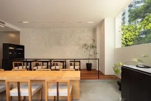 A dining area in a restaurant with a wooden table surrounded by chairs, potted plants, and stone walls, creating a cozy atmosphere