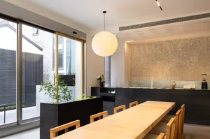 A warm and inviting dining space with a wooden table, potted plants, and natural light from a window