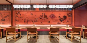 A modern restaurant dining area with two tables and chairs, surrounded by red walls and a warm atmosphere