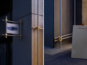 A commercial space with signs on a building and a sign on a pole, featuring walls, pipes, and other design elements