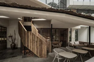 Inviting restaurant space with a wooden staircase, chairs, and dining tables, creating a welcoming atmosphere for guests
