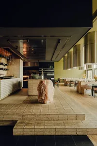 Modern kitchen with a large rock centerpiece, black countertops, and wine glasses, featuring a contemporary design and inviting atmosphere