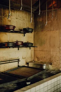 Rustic kitchen with hanging pots and pans, various bowls, and a cluttered atmosphere