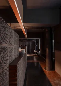 A modern kitchen with a wooden countertop, metal accents, and a dining table with chairs, set in a dimly lit space