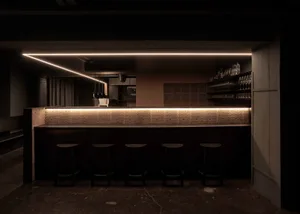 A modern bar area with a black countertop, brown wall, and four stools, creating an inviting and comfortable atmosphere