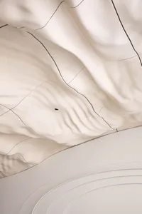 A modern interior space with a white ceiling featuring a wave-like pattern made of fabric, creating a contemporary atmosphere