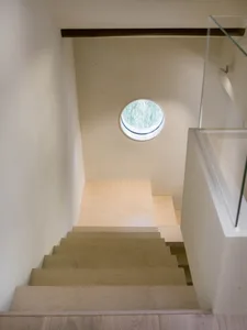 A real photo of a wooden staircase with a window at the bottom, providing natural light and a sense of depth and dimension