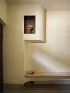 A solemn interior space with a bench against a wall featuring a small alcove with a skull, adding a unique decorative touch