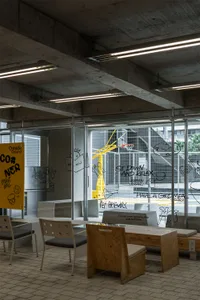 Modern lobby with a glass wall, chairs, a dining table, and a couch, surrounded by openness and functionality