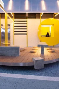 A modern public space with a circular design, featuring yellow walls, benches, and a warm atmosphere