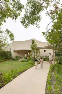 A family enjoys a relaxed outdoor gathering on a patio with a white building in the background