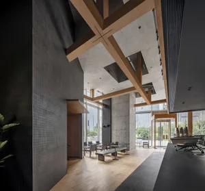 Open living area with wooden floors and walls, featuring chairs, potted plants, and a warm atmosphere