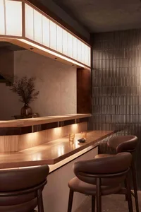 Warm and inviting bar area with a wooden countertop, brown leather chair, and decorative vases and cups