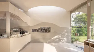 Modern interior space with curved walls, concrete floors, and potted plants, featuring two people