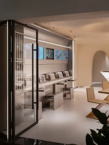Open living area with white walls, flooring, and furniture, featuring a TV and dining table