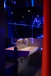 Bathroom with a metal sink, a mirror with an unusual design, and a red curtain adding a pop of color