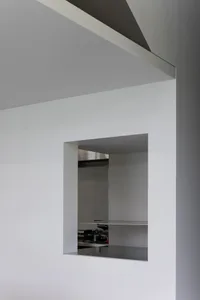 Empty modern kitchen with white walls, metal countertops, and two sinks, giving a clean and minimalistic atmosphere