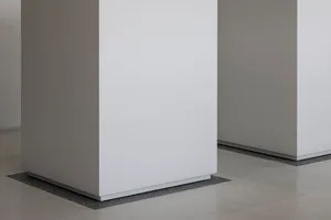 Empty white room with a large concrete wall, minimalist and serene atmosphere