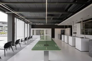 Modern open concept kitchen and dining area with a glass-topped island, white tile flooring, and sleek furniture