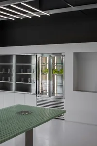 Modern kitchen with a stainless steel refrigerator, a table, and lined up cups on the countertop