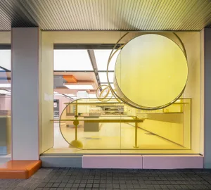 A busy cafe with yellow decor, artwork on the walls, and tables and chairs arranged for dining