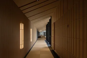 Empty hallway with wooden walls and flooring, lit by two lights on either side