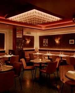 Sophisticated dining space with brown tables and chairs, wine glasses, and well-lit areas
