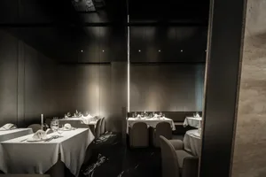 Elegant dining space with silver metal walls, rows of tables and chairs, and wine glasses on some tables