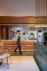 A modern restaurant interior with a counter featuring wood elements, marble, and various items, set in a comfortable and inviting atmosphere