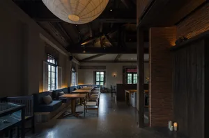 Open restaurant interior with multiple tables, couches, and wood elements, creating a cozy atmosphere with warm lighting