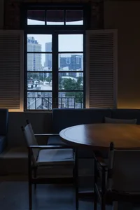 Cozy living space with a large window offering a panoramic city view, two chairs, and a dining table