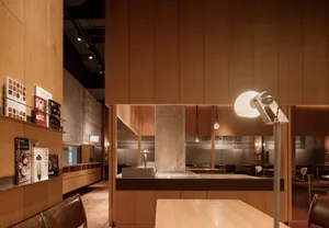 A modern kitchen with wooden floors and walls, featuring a dining table, chairs, and a sink, creating a warm and inviting atmosphere