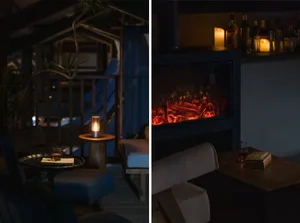 Cozy modern living space with chairs, a dining table, fireplace, and potted plant, lit by warm nighttime lighting